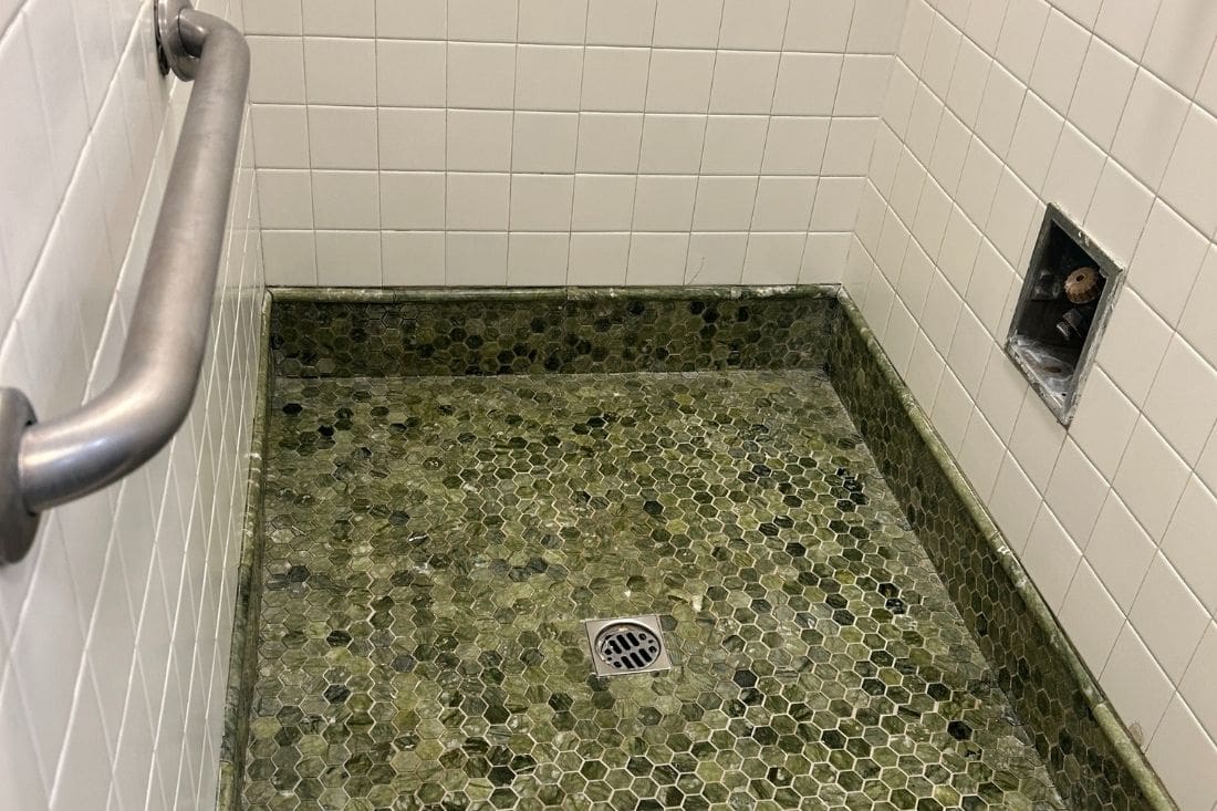 Restored marble shower floor in Los Angeles featuring polished jade green marble tile, showcasing a clean and refreshed surface after professional restoration.