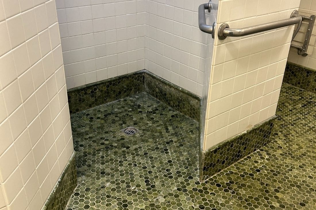 Restored marble shower area in Los Angeles, showcasing polished green mosaic marble tiles with a clean, rejuvenated finish after professional restoration.